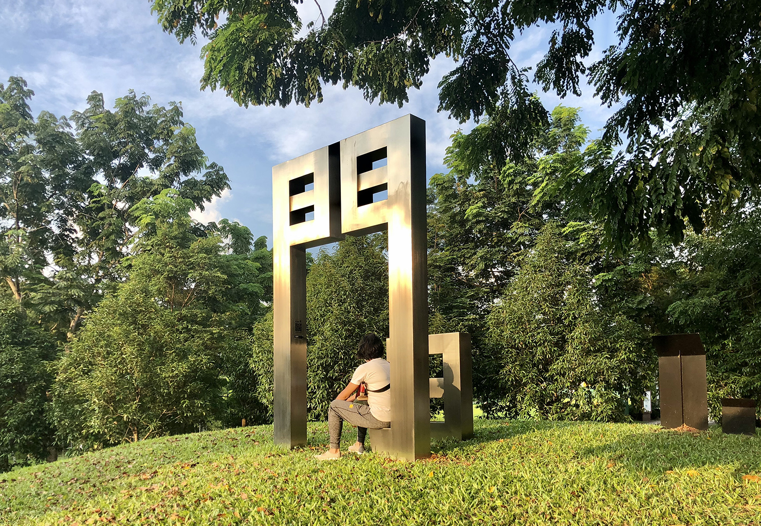 a park goer sitting by the jian rewritten public art sculpture